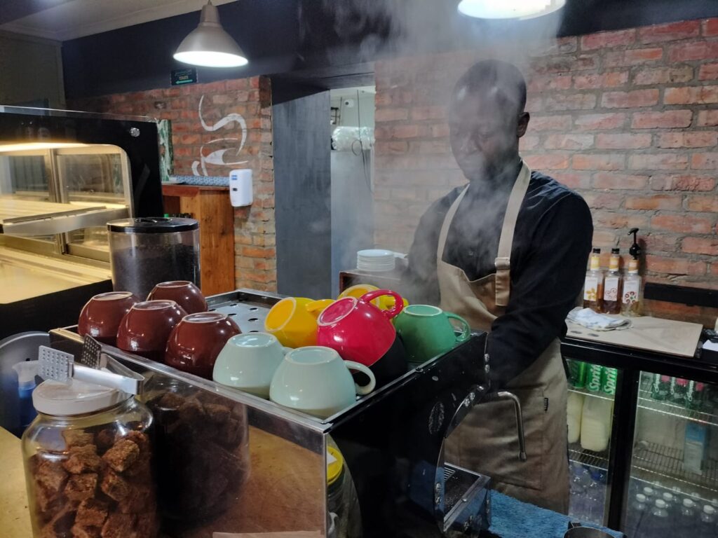 Barista steaming milk behind the counter at My Hometown Café