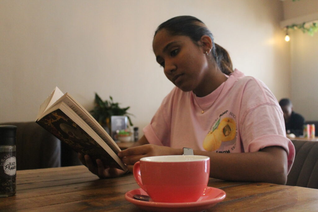 Person reading a book with coffee at My Hometown Café in Newton Park, Port Elizabeth